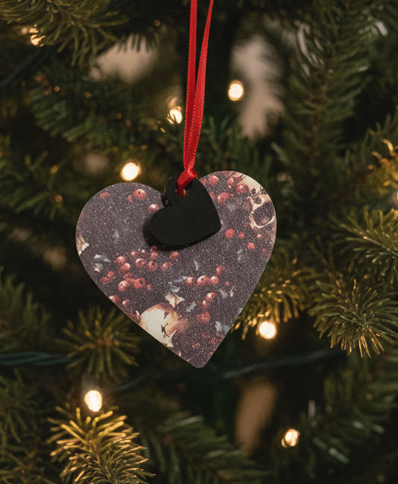 Heart-shaped decorative item with a red string on a textured white background